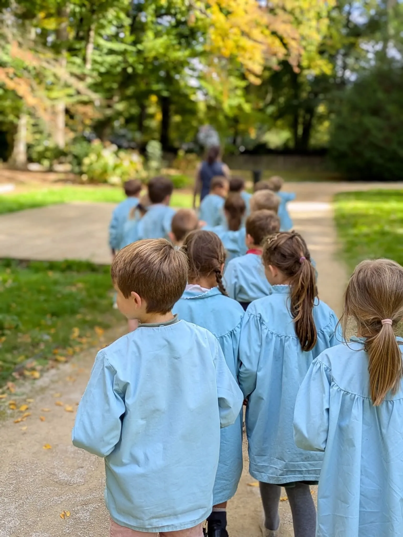 Les élèves en blouse sur une allée du parc de l'école