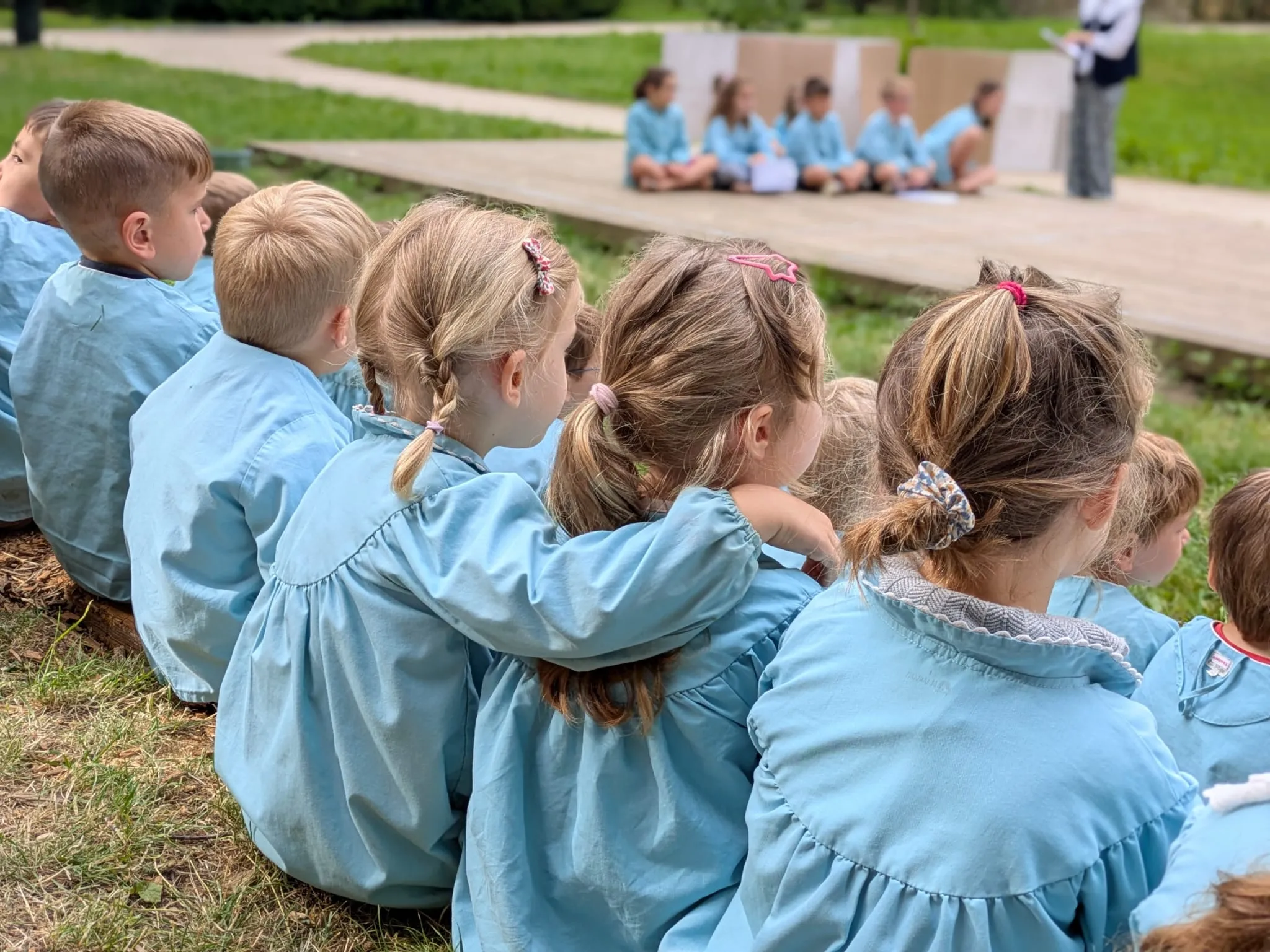 Deux petites élèves assises dans l'herbe, un bras sur l'épaule l'une de l'autre